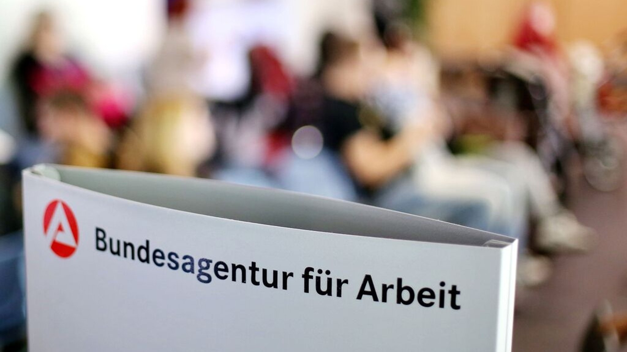Ein Schild mit der Aufschrift "Bundesagentur für Arbeit" steht einem vollen Wartezimmer im Jobcenter. | Bild: dpa-Bildfunk/Jan Woitas Ein Schild mit der Aufschrift "Bundesagentur für Arbeit" steht einem vollen Wartezimmer im Jobcenter.