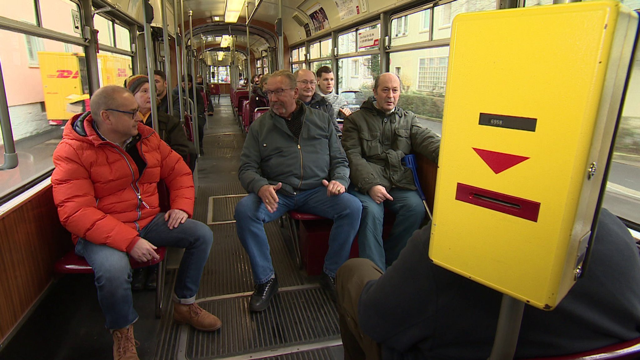 Alte Straßenbahn von innen. Es ist eng, der Gang ist schmal.