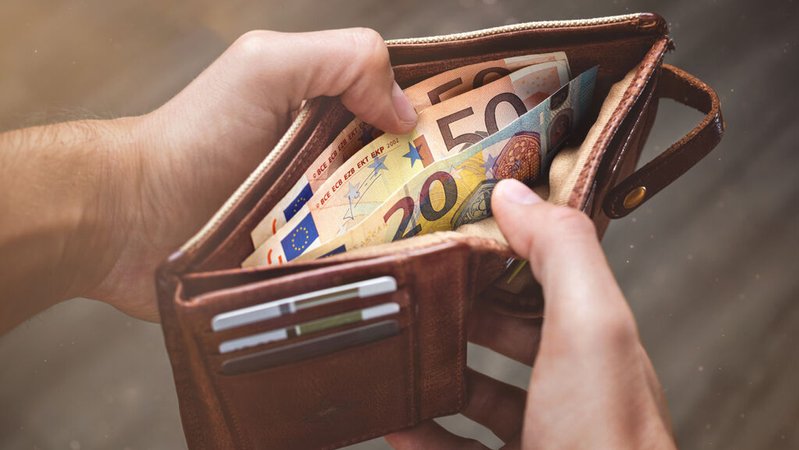 Ein Mann öffnet einen Geldbeutel. | Bild: stock.adobe.com/photoschmidt Ein Mann öffnet einen Geldbeutel.