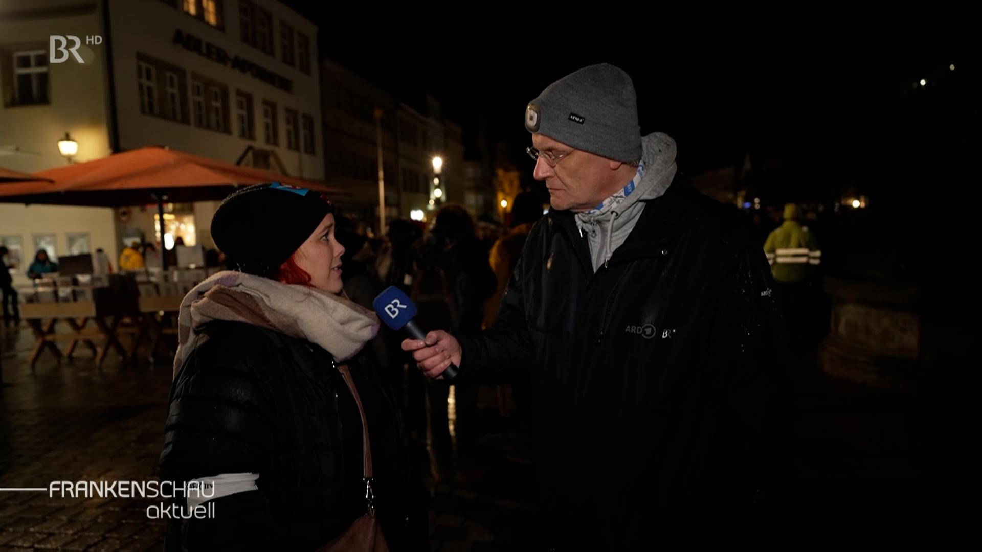 Ein Reporter des BR interviewt in der Dunkelheit eine Frau. 