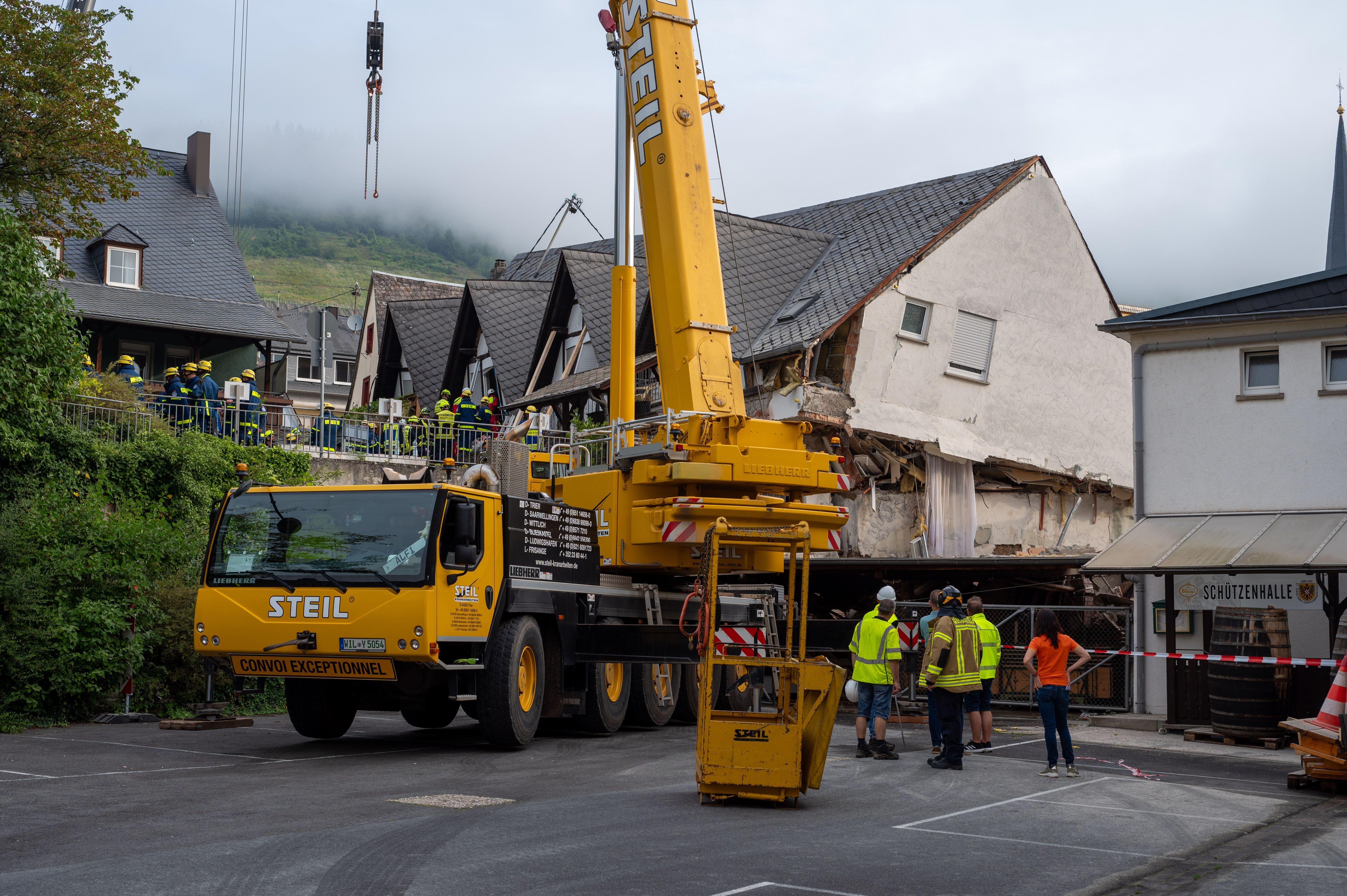 Ein großer Kran steht vor dem halb eingestürzten Hotel an der Mosel