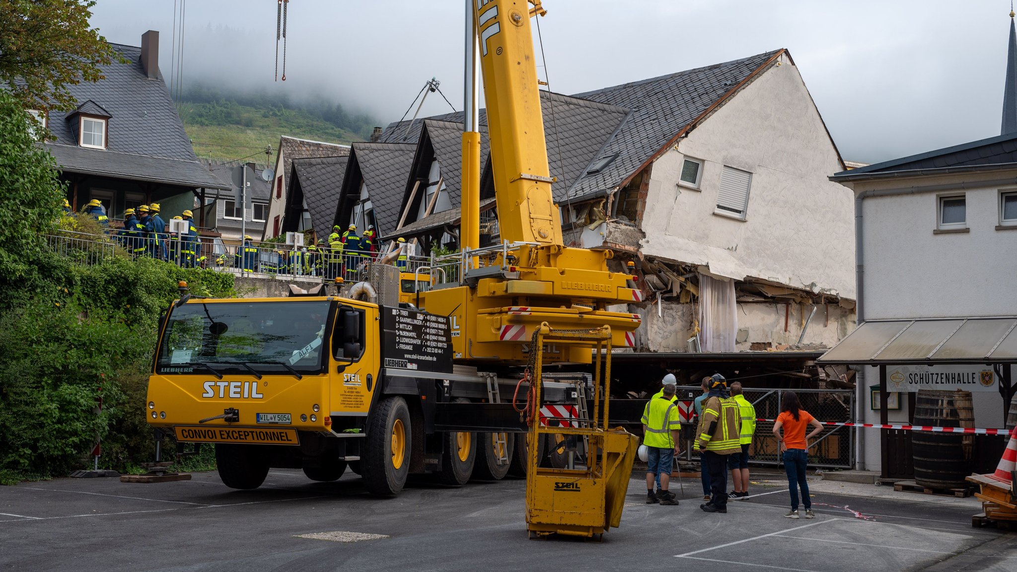 Ein großer Kran steht vor dem halb eingestürzten Hotel an der Mosel