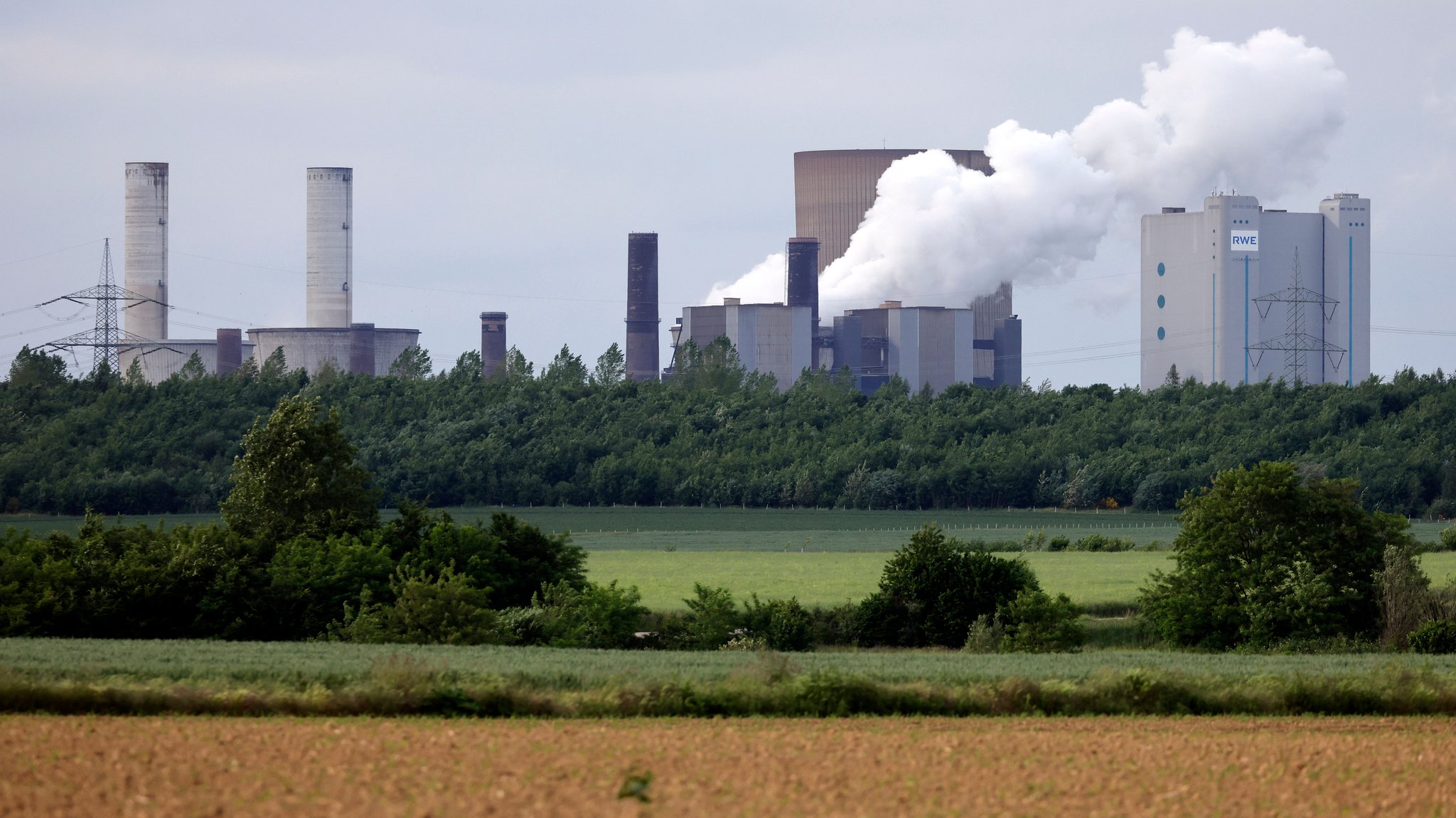 Das Kohlekraftwerk Niederaußem und umliegende Stromleitungen zeichnen sich gegen die untergehende Sonne ab.