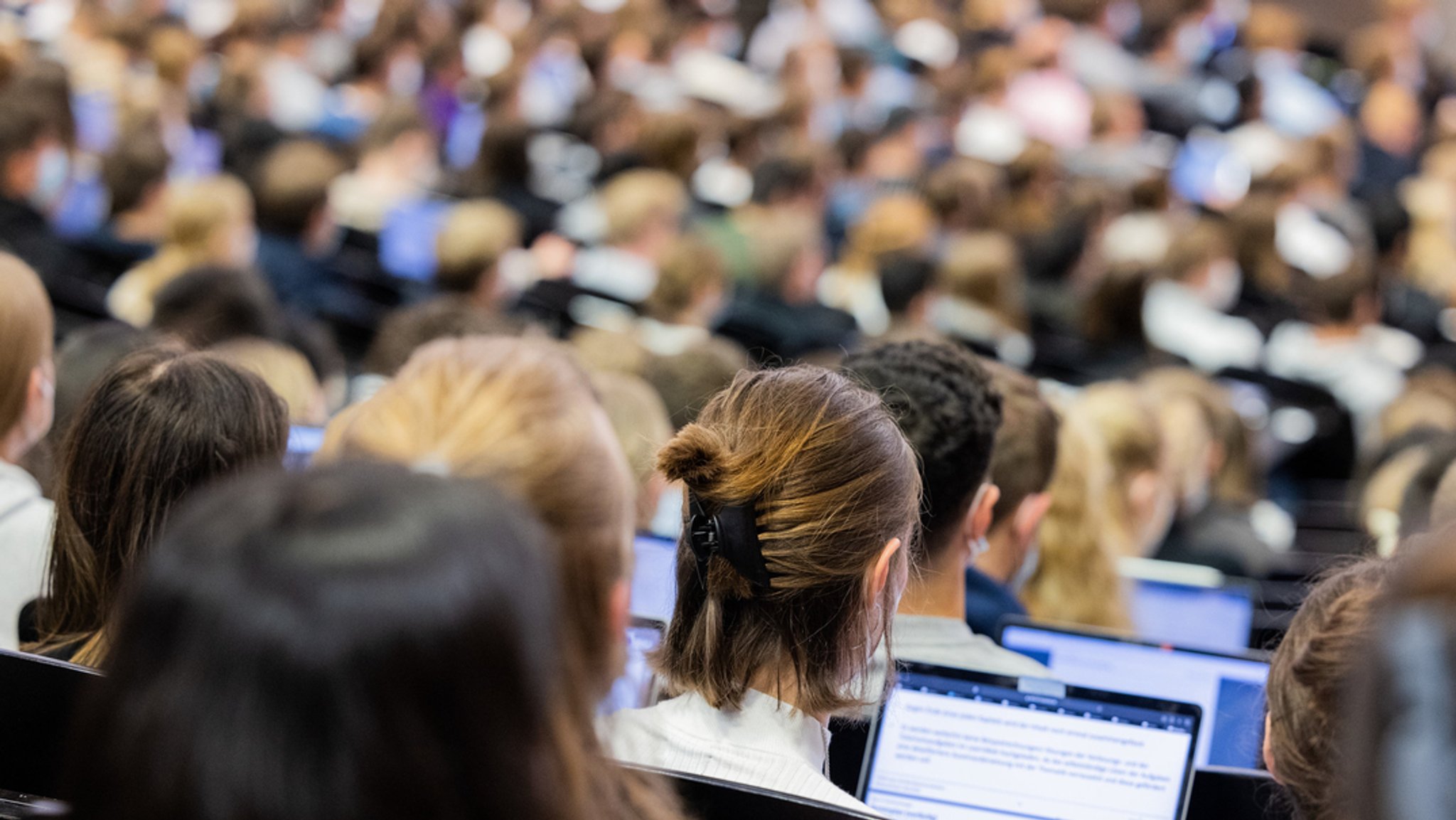 Studentinnen und Studenten sitzen während einer Vorlesung in einem Hörsaal.