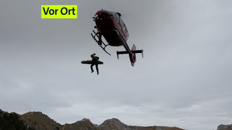 Zu sehen ist ein Helikopter, der per Seilwinde einen Soldaten und eine Trage emporhebt. | Bild: BR/Kilian Neuwert Zu sehen ist ein Helikopter, der per Seilwinde einen Soldaten und eine Trage emporhebt.