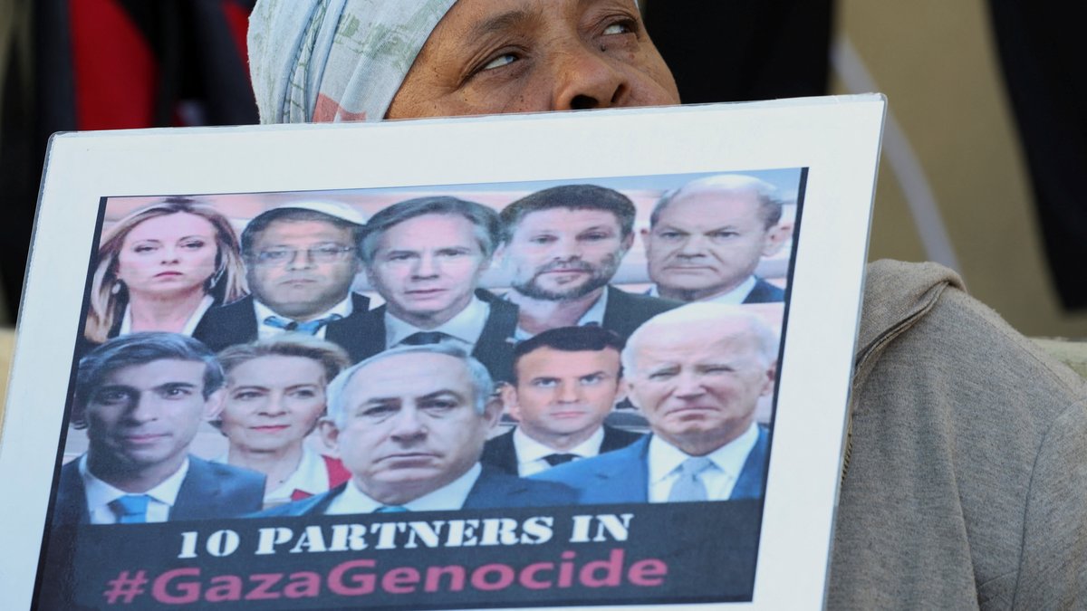 Frau hält Schild mit angeblichen "Völkermords-Unterstützern" aus der Politik