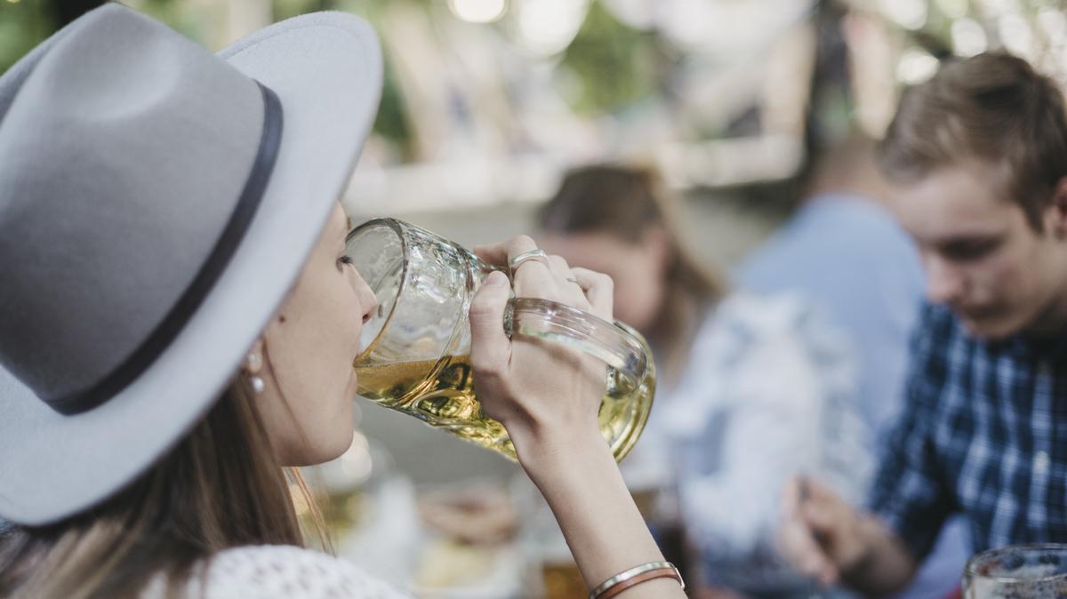 Eine Frau trinkt in einem Biergarten eine Mass Bier.