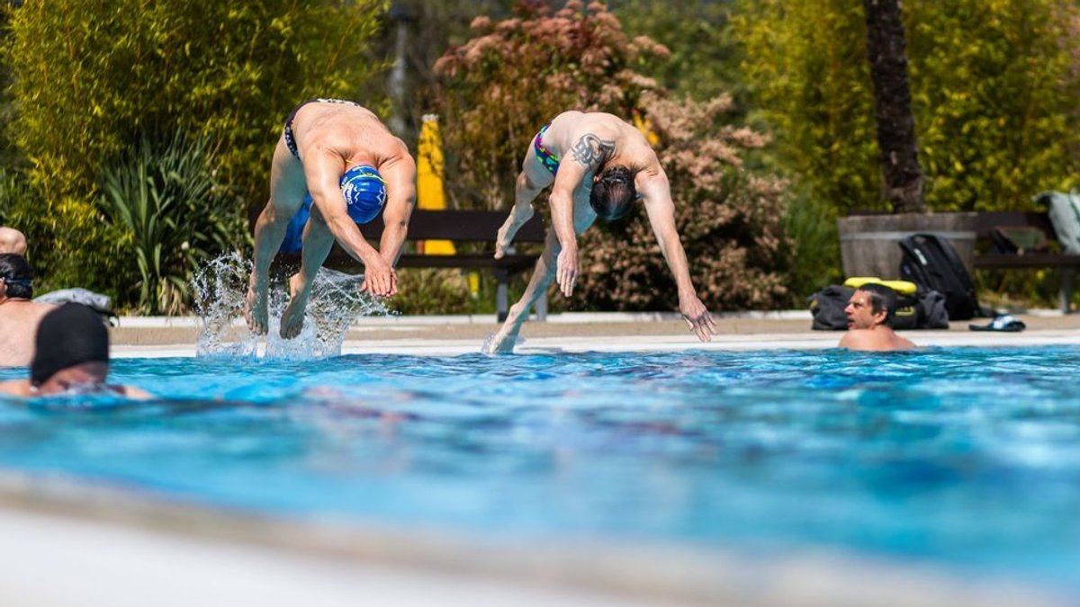 Zwei Männer springen per Kopfsprung in ein Freibad.