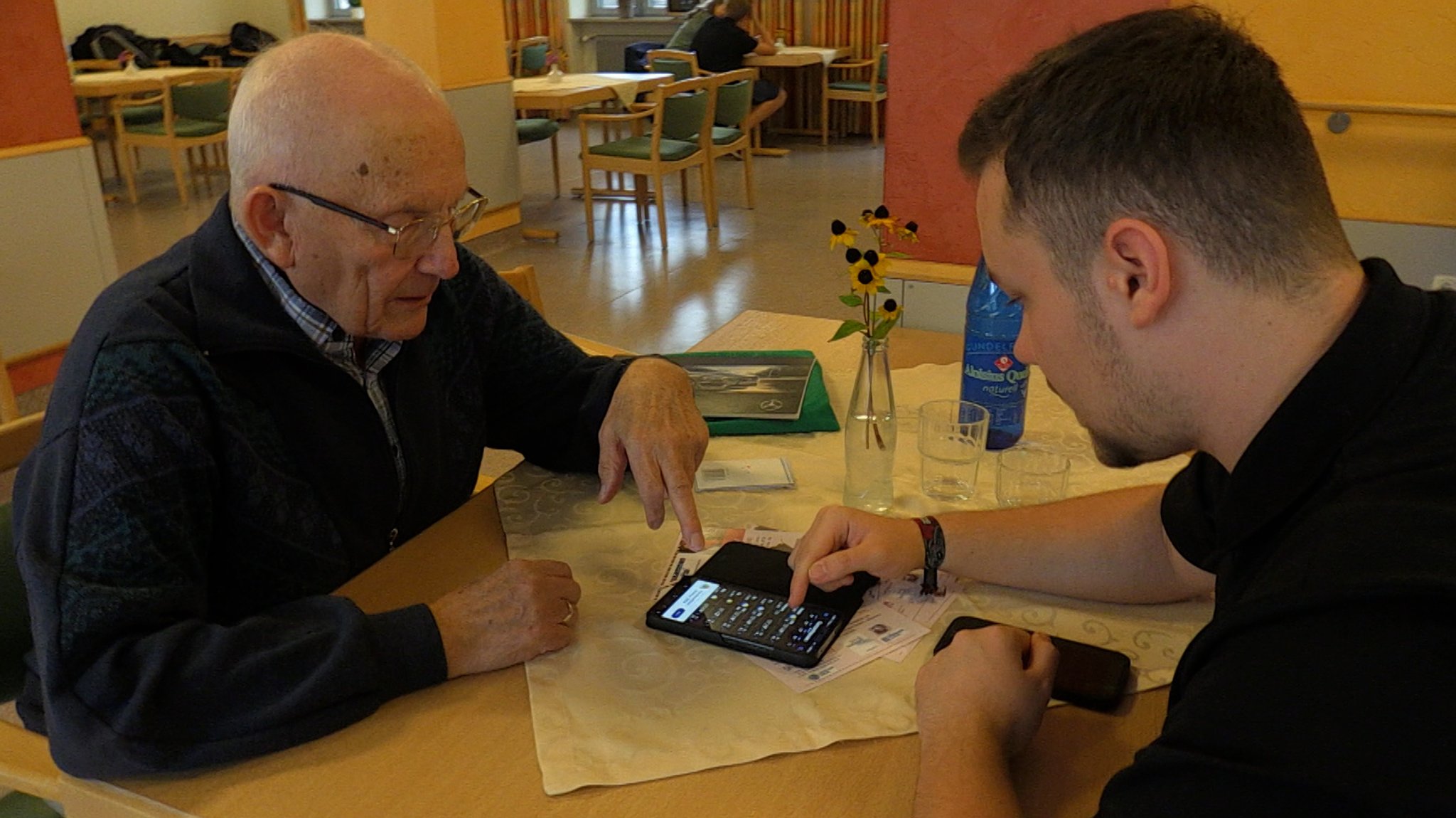 Maxim (rechts) hilft Karl Lechner mit seinem Smartphone. 