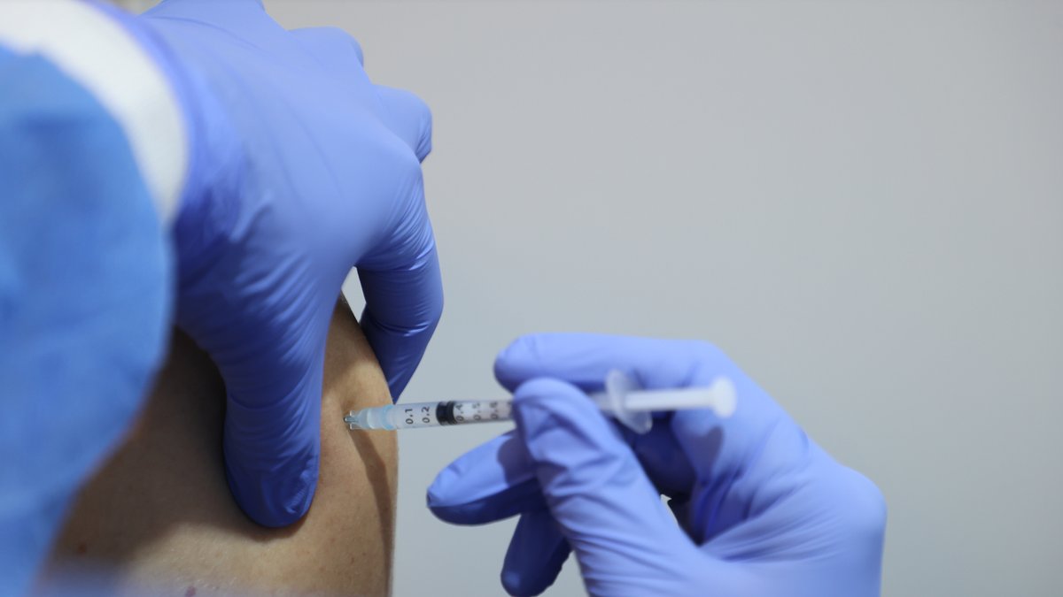 Ein medizinischer Mitarbeiter impft mit einer Spritze und dem Impfstoff von Biontech einen Mann in einem thüringischen Kongresszentrum (Symbolbild).. 