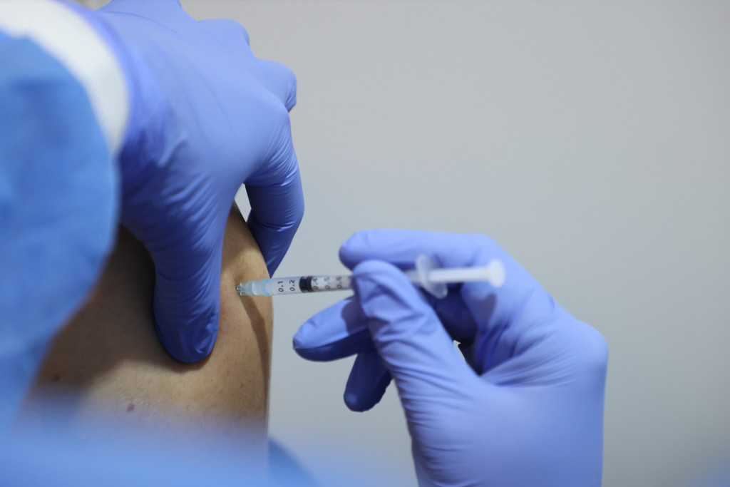 Ein medizinischer Mitarbeiter impft mit einer Spritze und dem Impfstoff von Biontech einen Mann in einem thüringischen Kongresszentrum (Symbolbild).. 