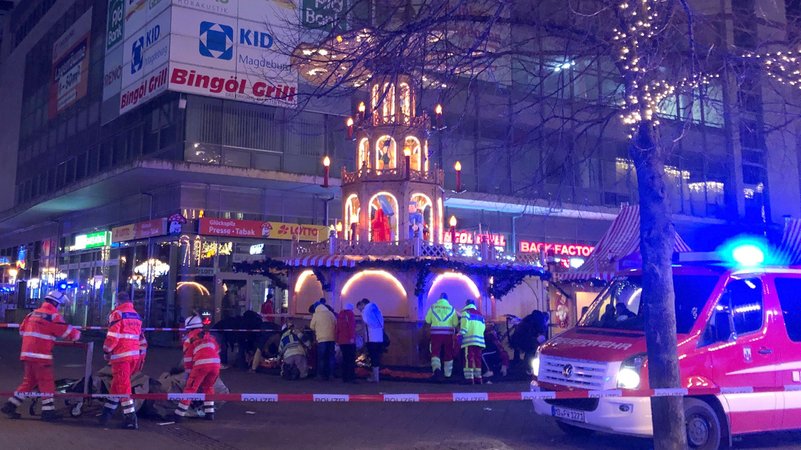 Rettungskräfte in orangener und rot-neongelber Montur sind auf einem abgesperrten Platz beschäftigt. Im rechten Vordergrund ein Feuerwehrfahrzeug, im Hintergrund eine mehrstöckige Weihnachtspyramide. In Magdeburg ist ein Autofahrer in eine Menschengruppe auf dem Weihnachtsmarkt gefahren. | Bild: picture alliance/dpa/dpa-Zentralbild | Dörthe Hein Rettungskräfte in orangener und rot-neongelber Montur sind auf einem abgesperrten Platz beschäftigt. Im rechten Vordergrund ein Feuerwehrfahrzeug, im Hintergrund eine mehrstöckige Weihnachtspyramide. In Magdeburg ist ein Autofahrer in eine Menschengruppe auf dem Weihnachtsmarkt gefahren.