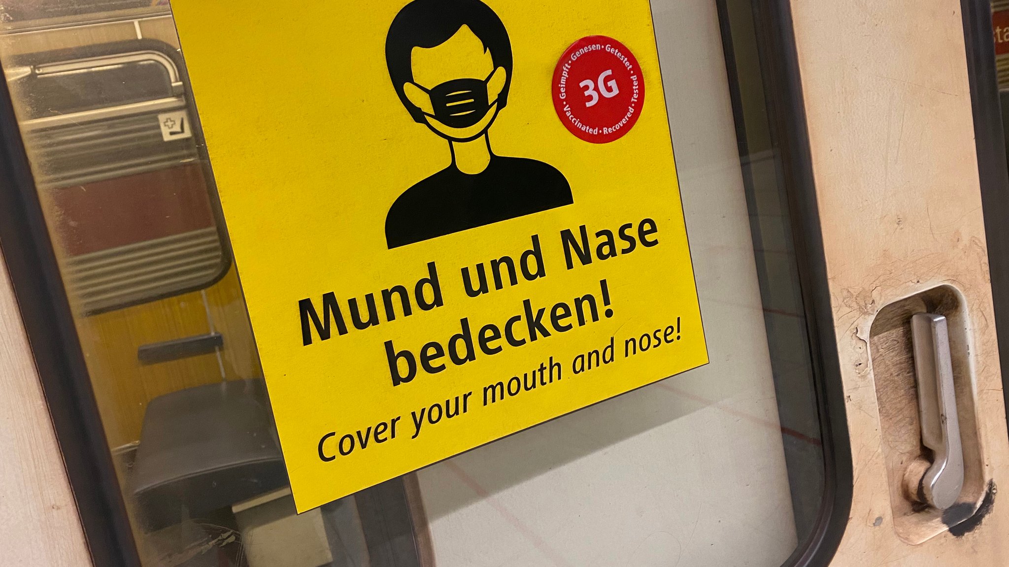 Hier gelten weiter Maskenpflicht und 3G-Regel: Hinweisschild auf einer Münchner U-Bahn-Tür.