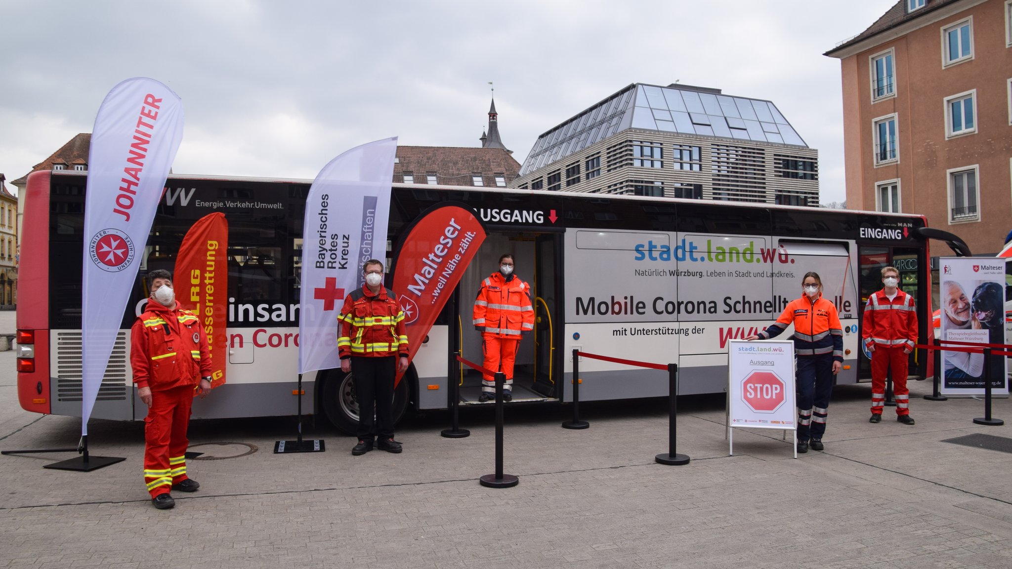 Helfer von DLRG, Freiwilliger Feuerwehr, Johannitern, Maltesern und Rotem Kreuz vor dem Corona-Testbus am Unteren Markt.