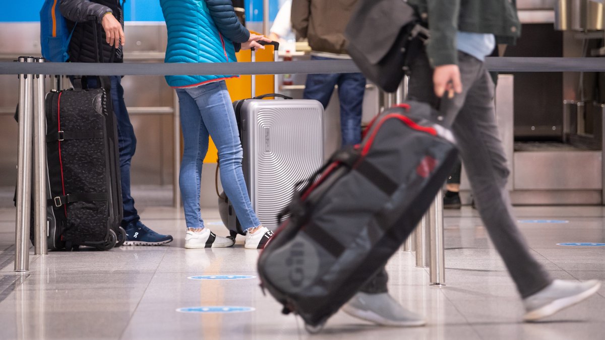 Reisende mit Koffern an einem Check-In-Schalter am Flughafen München