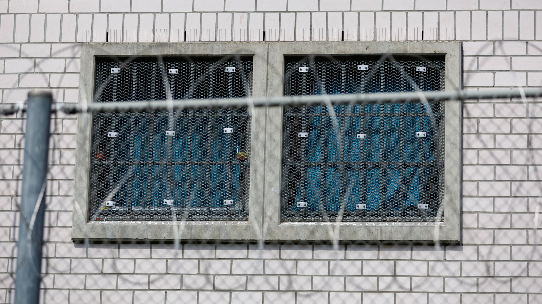 Stacheldraht vor einem vergitterten Fenster einer Justizvollzugsanstalt.