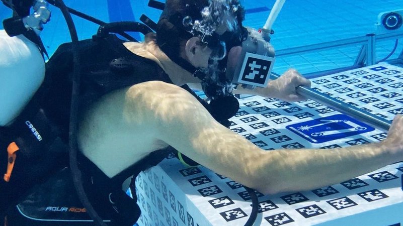 Professor Andreas Nüchter testet im Schwimmbad der Uni Würzburg die neue VR-Anwendung vor einem abgesenkten, mit Tracking-Codes versehenen Block.