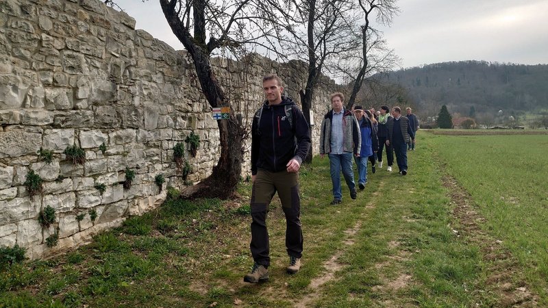 Eine Gruppe Wandernde gehen an der alten Klostermauer in Engelthal vorbei.