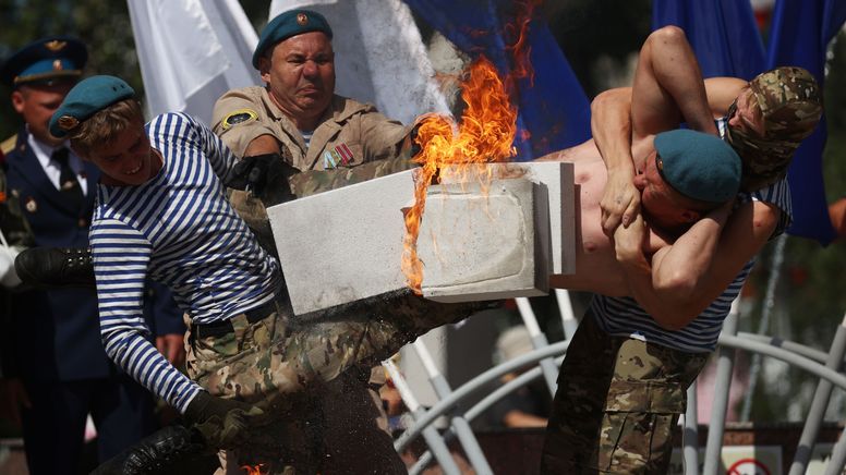 Männer zerstören Betonstein auf dem Bauch eines Kameraden | Bild:Kirill Kukhmar/Picture Alliance