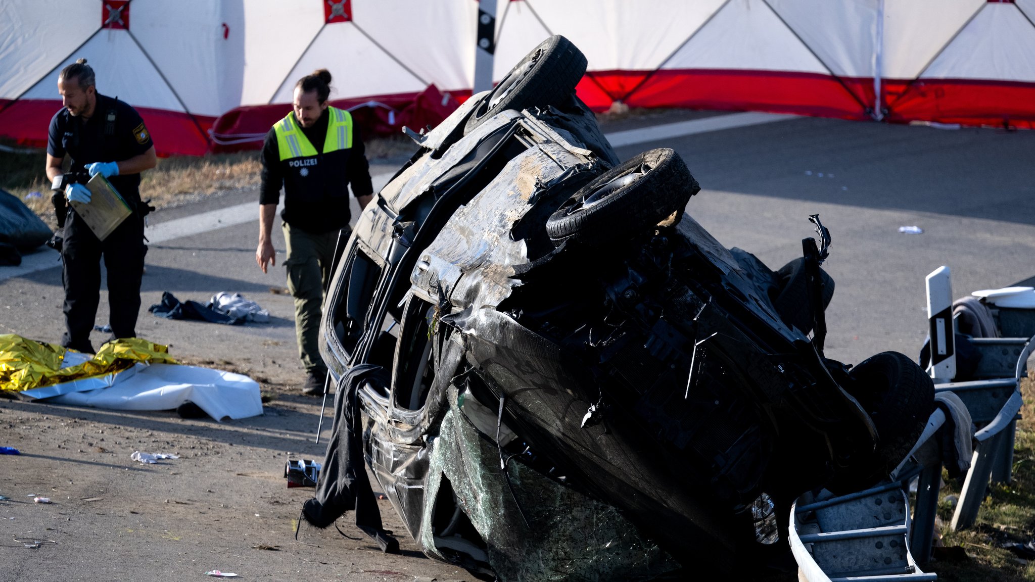 Polizisten ermitteln am umgestürzten Fahrzeug. Beim Unfall eines mutmaßlichen Schleuserfahrzeugs auf der Autobahn 94 sind sieben Menschen gestorben und mehrere schwer verletzt worden. 