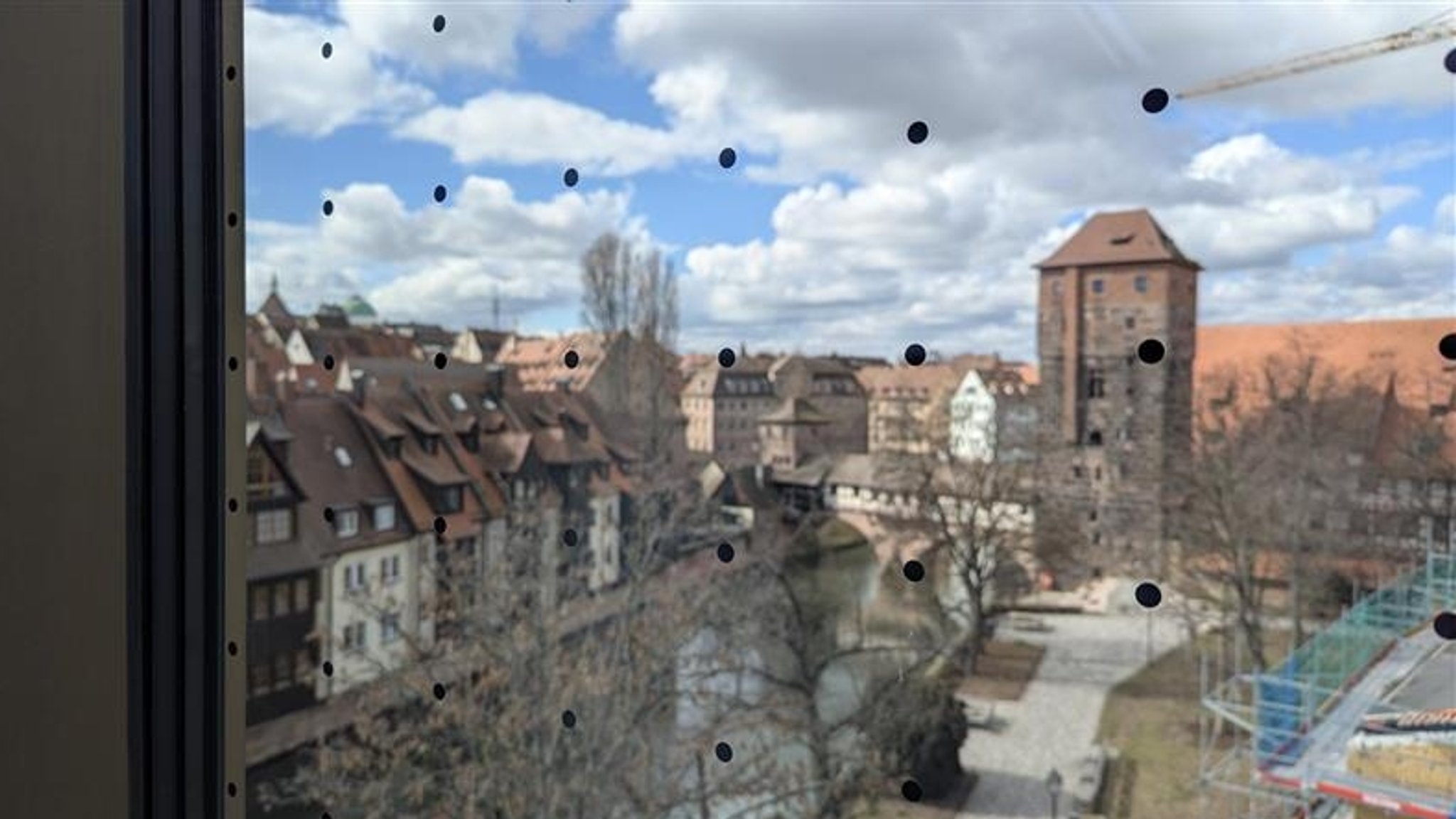 Schwarze Punkte auf einer Fensterfront dahinter die Silhouette von Nürnberg