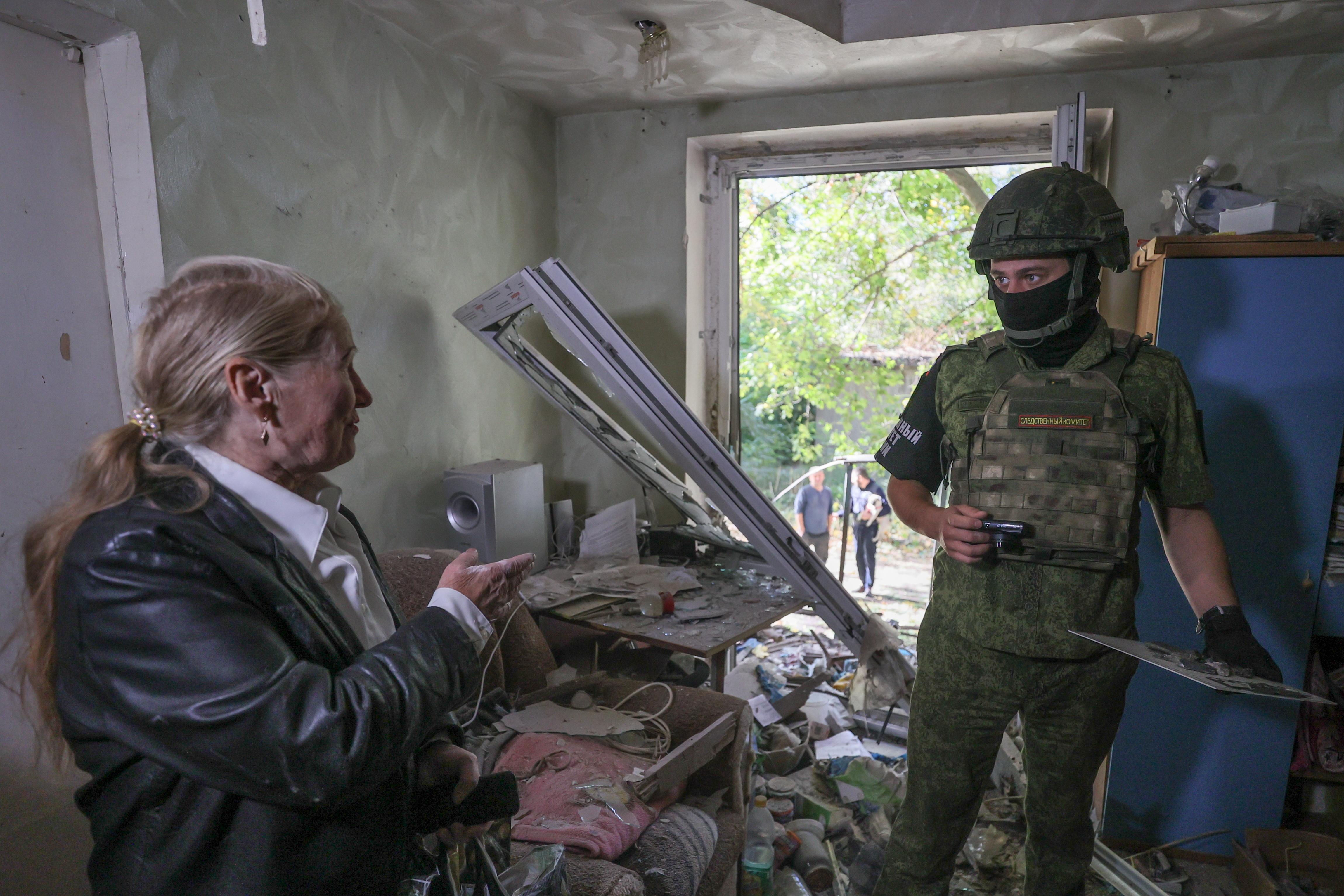 Frau steht in zerstörter Wohnung 