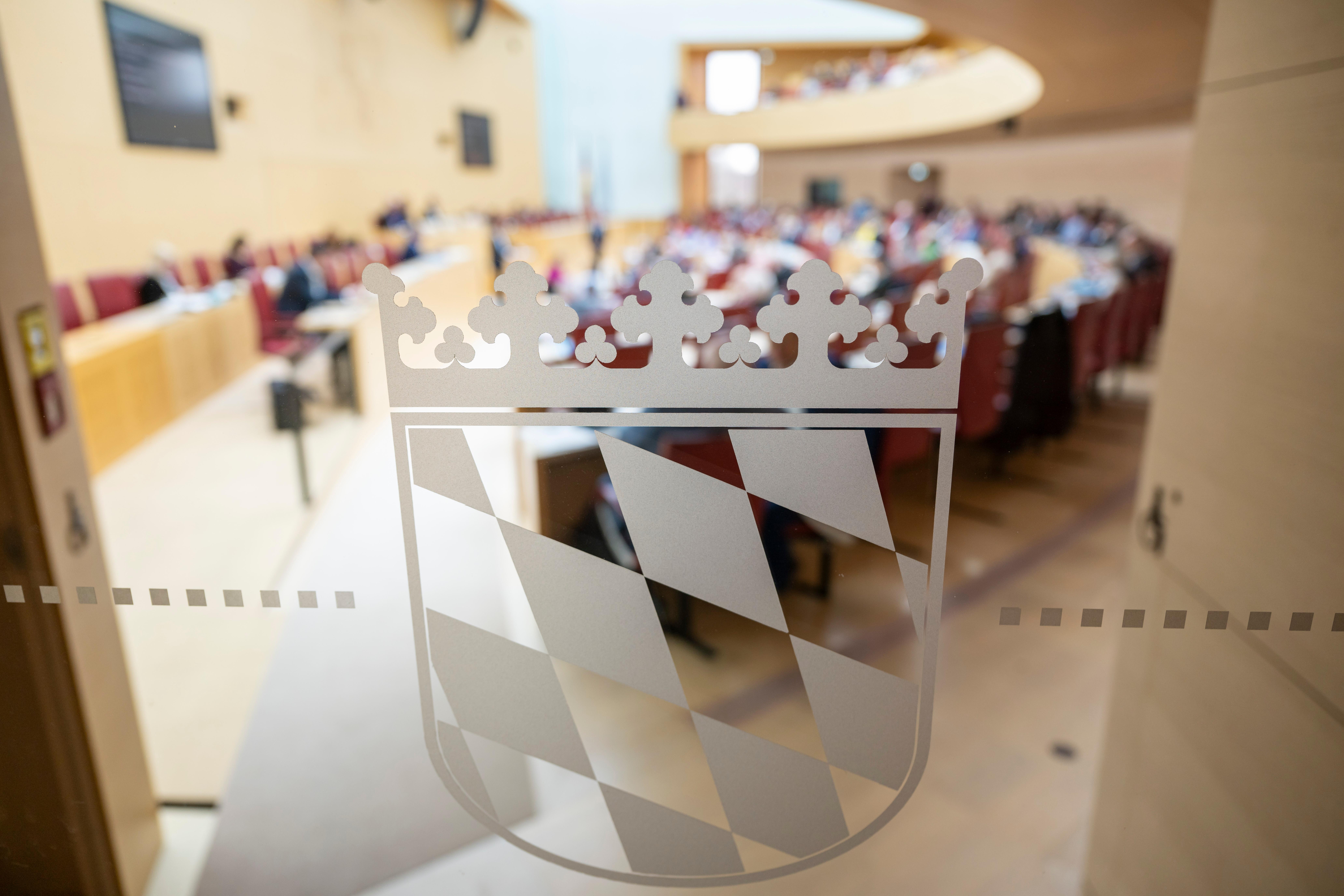 Das bayerische Wappen klebt an einer Glastür zum Plenarsaal im bayerischen Landtag.