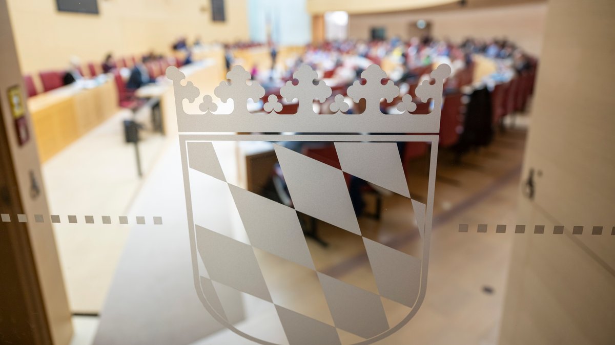 Das bayerische Wappen klebt an einer Glastür zum Plenarsaal im bayerischen Landtag.