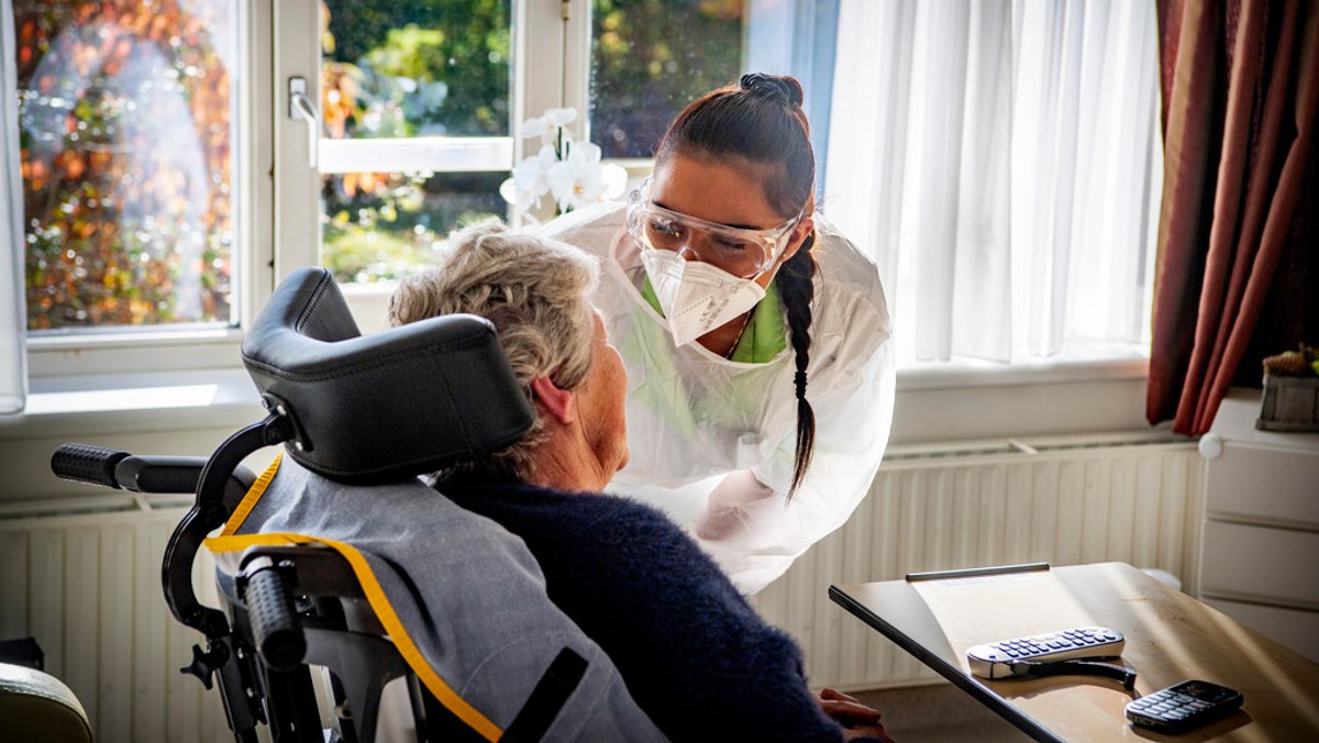 Eine Pflegerin spricht mit einer älteren Frau im Rollstuhl (Symbolbild).