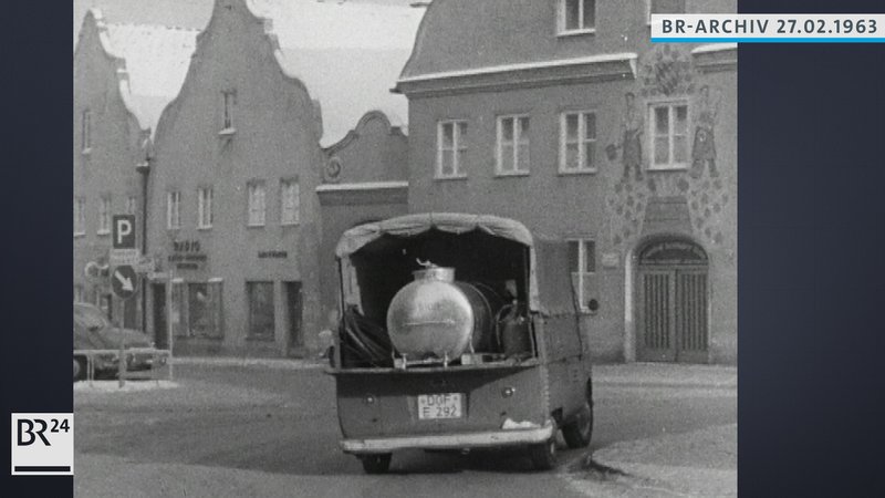 Ein VW-Transporter mit offener Ladefläche transportiert ein Fass mit Trinkwasser für die Wasserversorgung der Anwohner
