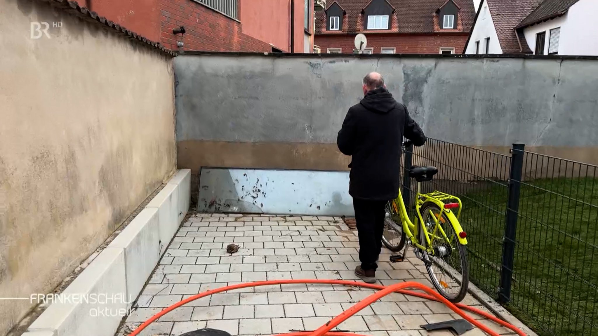 Uwe Heyder mit Rad vor Mauer.