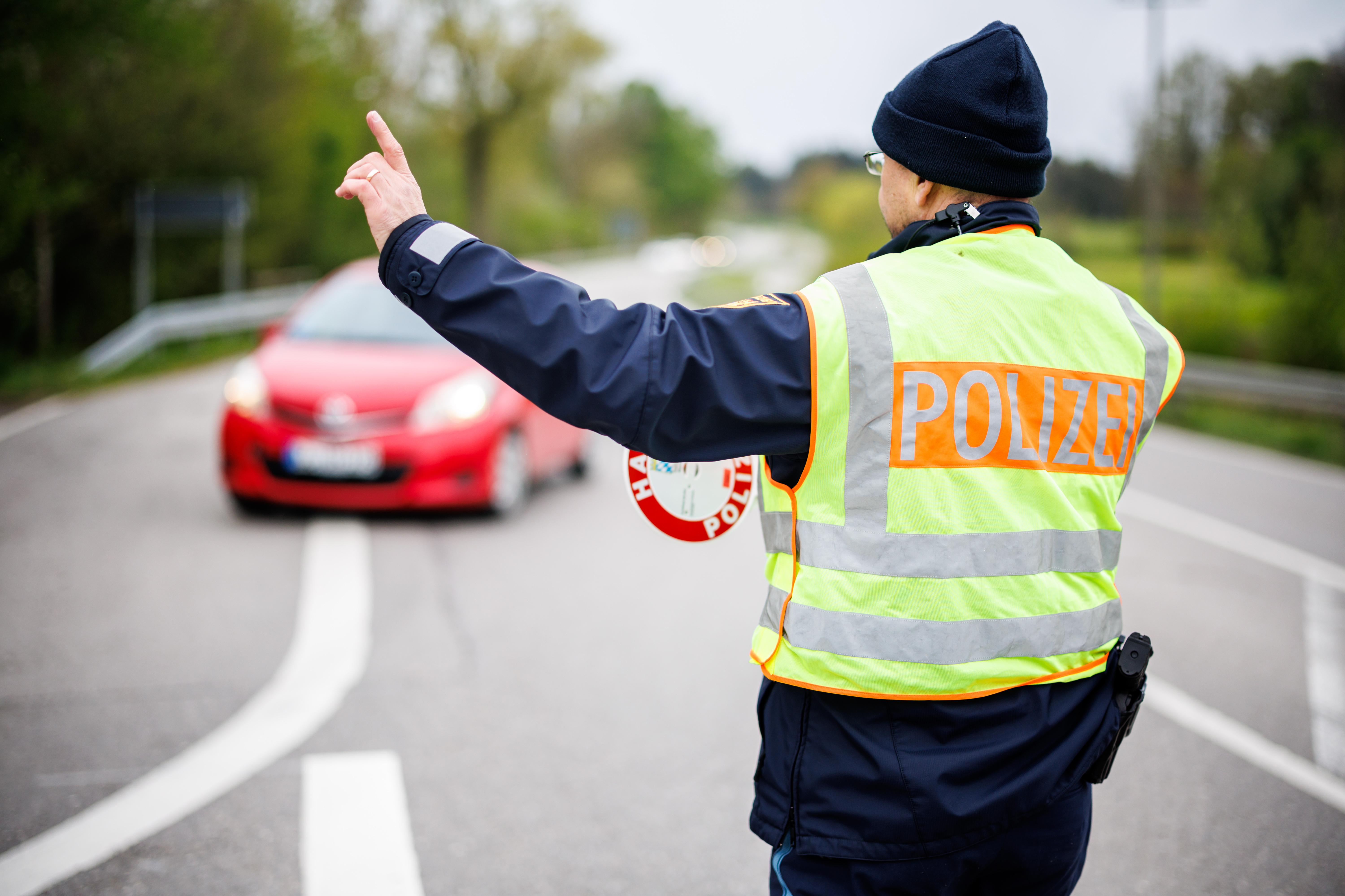 Ein Polizist winkt am 19.04.24 an einer Staatsstraße außerorts bei Wessobrunn (Bayern) ein Fahrzeug aus dem Verkehr (Symbolbild).