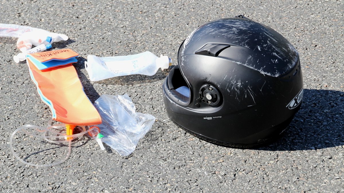 Abgeschrammter Motorradhelm und Medikamente auf der Straße (Symbolbild) 