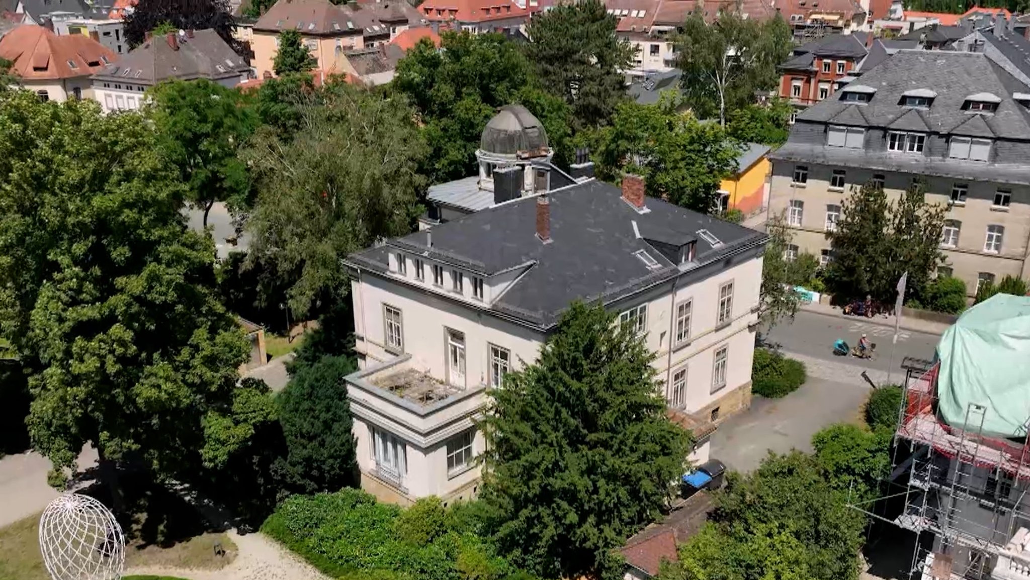 Blick von oben auf ein herrschaftliches Haus im Grünen. 