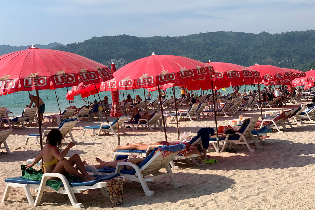 Touristen liegen unter Sonnenschirmen am Patong Beach.