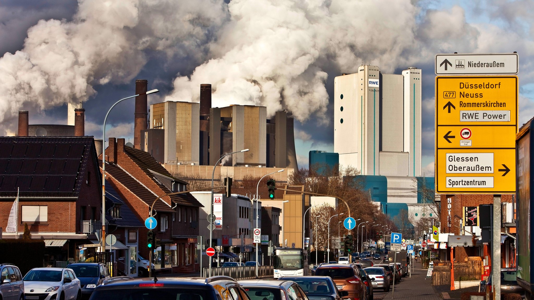 Eine Straße in Niederaussem mit Braunkohlekraftwerk im Hintergrund.