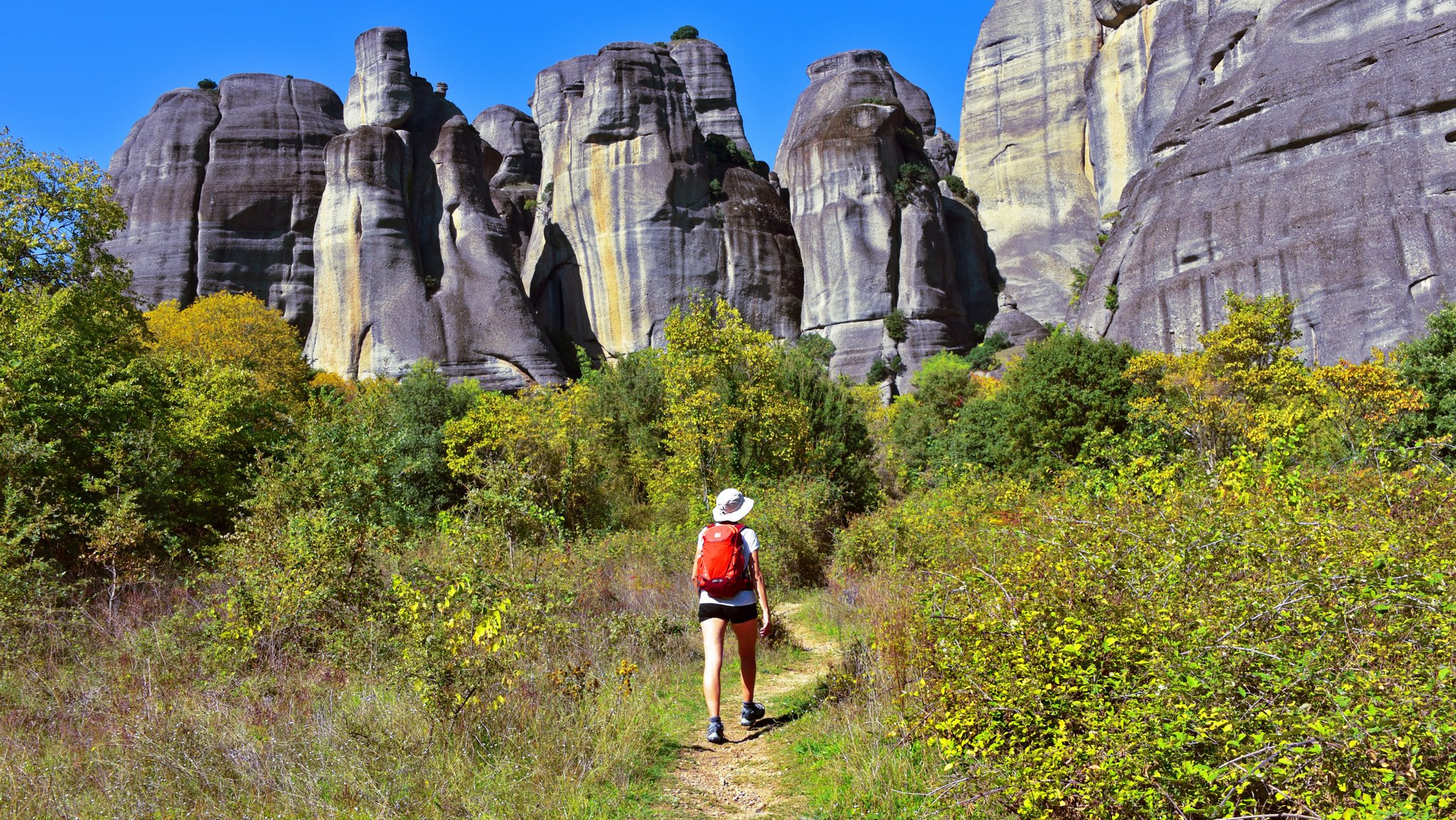 Eine Touristin geht unter wolkenlosem Himmel in Griechenland wandern