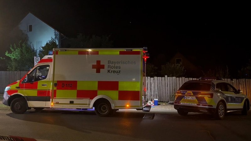 Am Tatort vor einem Holzbretterzaun stehen ein Polizeiauto und ein Rettungswagen. In der Nähe des Brombachsees ist ein 15-Jähriger mit einem Messer getötet worden. Tatverdächtig ist eine 19-Jährige. | Bild: Bayerischer Rundfunk 2025 Am Tatort vor einem Holzbretterzaun stehen ein Polizeiauto und ein Rettungswagen. In der Nähe des Brombachsees ist ein 15-Jähriger mit einem Messer getötet worden. Tatverdächtig ist eine 19-Jährige.