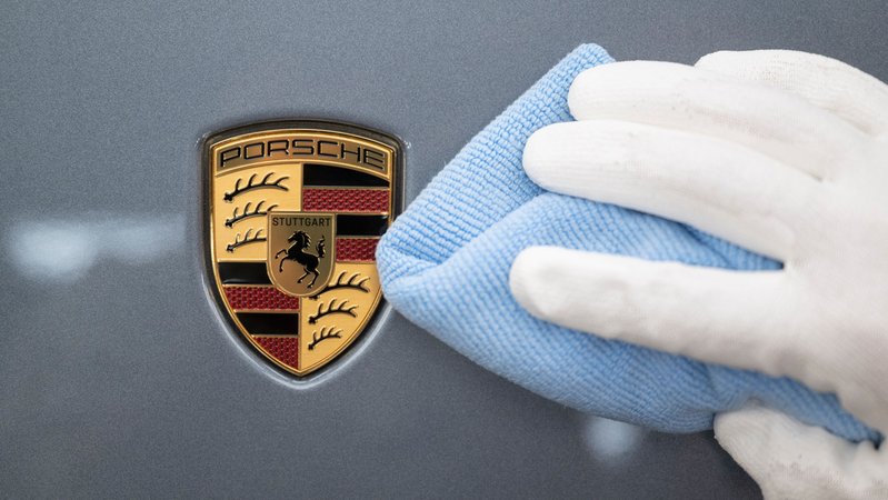 Ein Mitarbeiter der Porsche AG poliert im Stammwerk in Zuffenhausen ein Fahrzeug. Man sieht das Porsche-Emblem. | Bild: picture alliance/dpa | Marijan Murat Ein Mitarbeiter der Porsche AG poliert im Stammwerk in Zuffenhausen ein Fahrzeug. Man sieht das Porsche-Emblem.