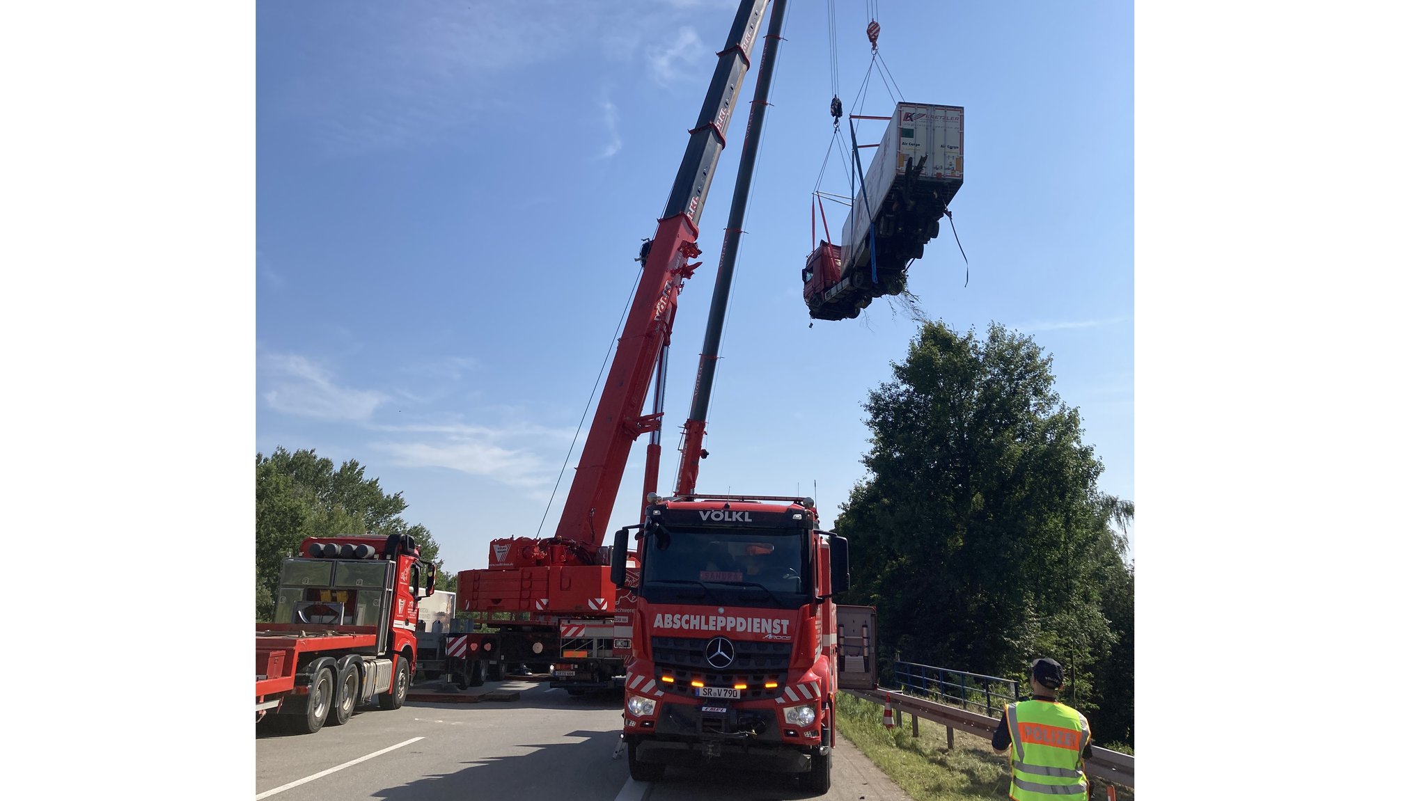 Wie ein Spielzeug-Lkw hängt der Sattelzug an dem Spezialkran