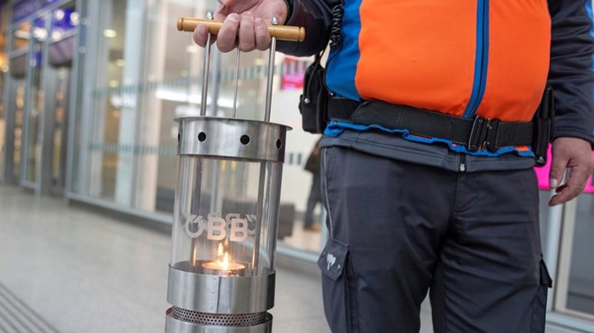 Ein Mitarbeiter des ÖBB trägt eine Kerze in einer Laterne.