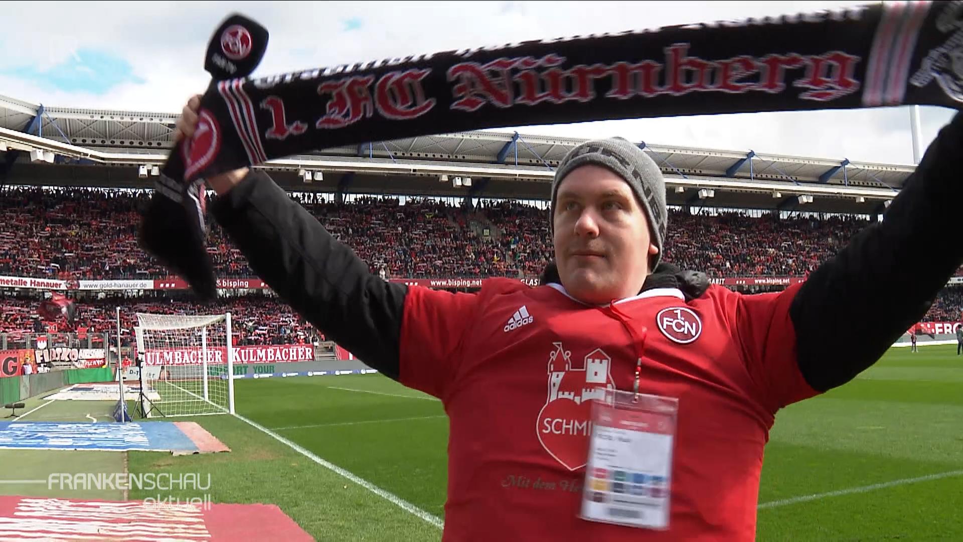 Ein Fußballfan steht mit seinem FCN-Schal auf dem Rasen im MAx-Morlock-Stadion.