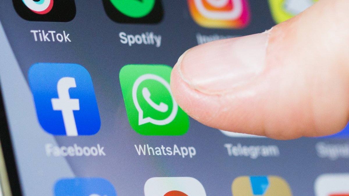 Finger drückt auf WhatsApp-Symbol auf einem Smartphone-Bildschirm