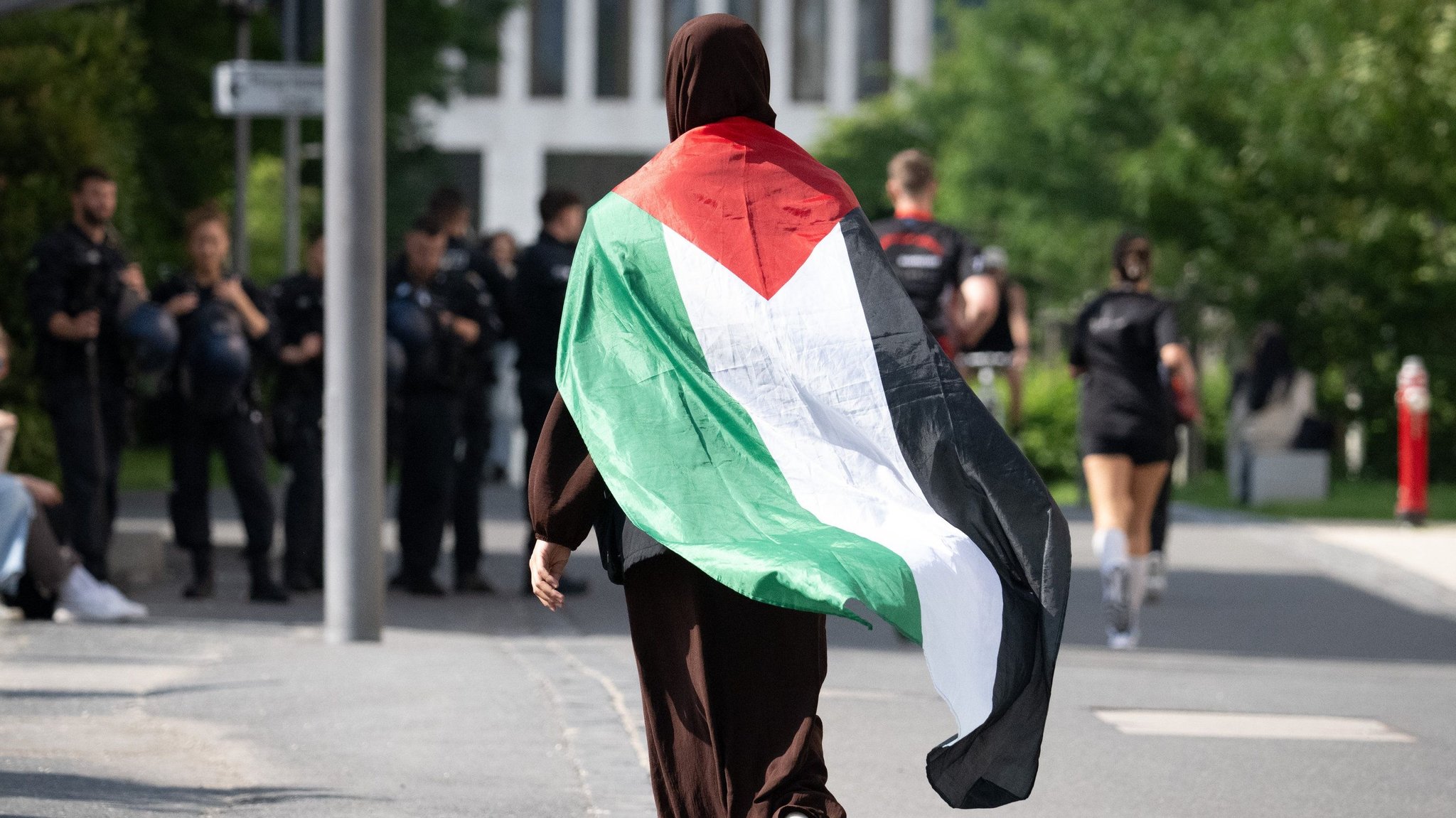 Eine Frau geht in Frankfurt am Main mit einer umgehängten Palästina-Fahne zu einer Demonstration (Archivbild)