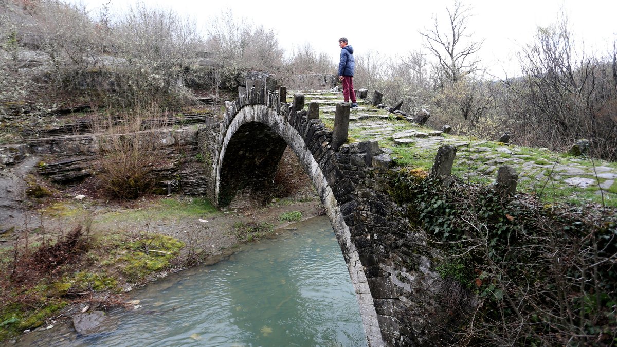 Ein Mensch geht über eine Brücke in der Region Zagori.
