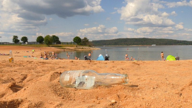Eine leere Bierflasche liegt am Strand des Brombachsees