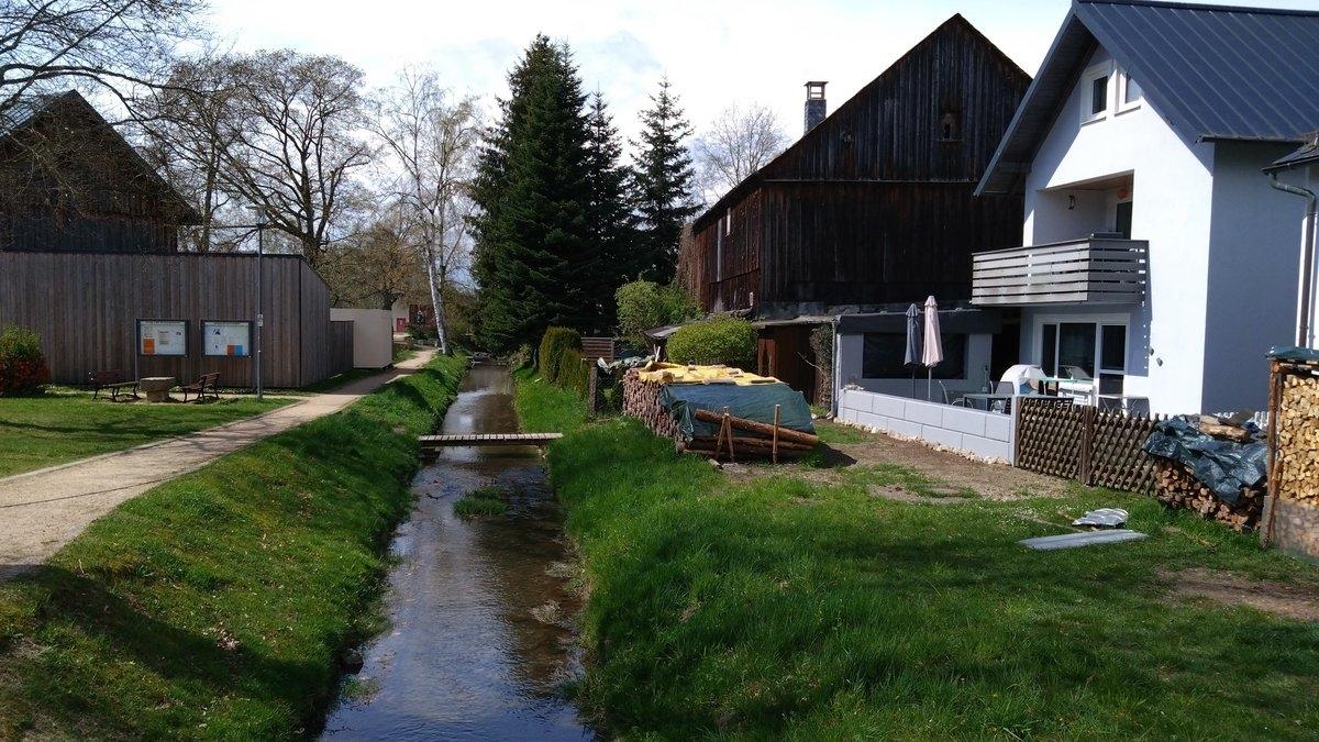 Ein kanalisierter Bachlauf direkt vor einem Haus. 