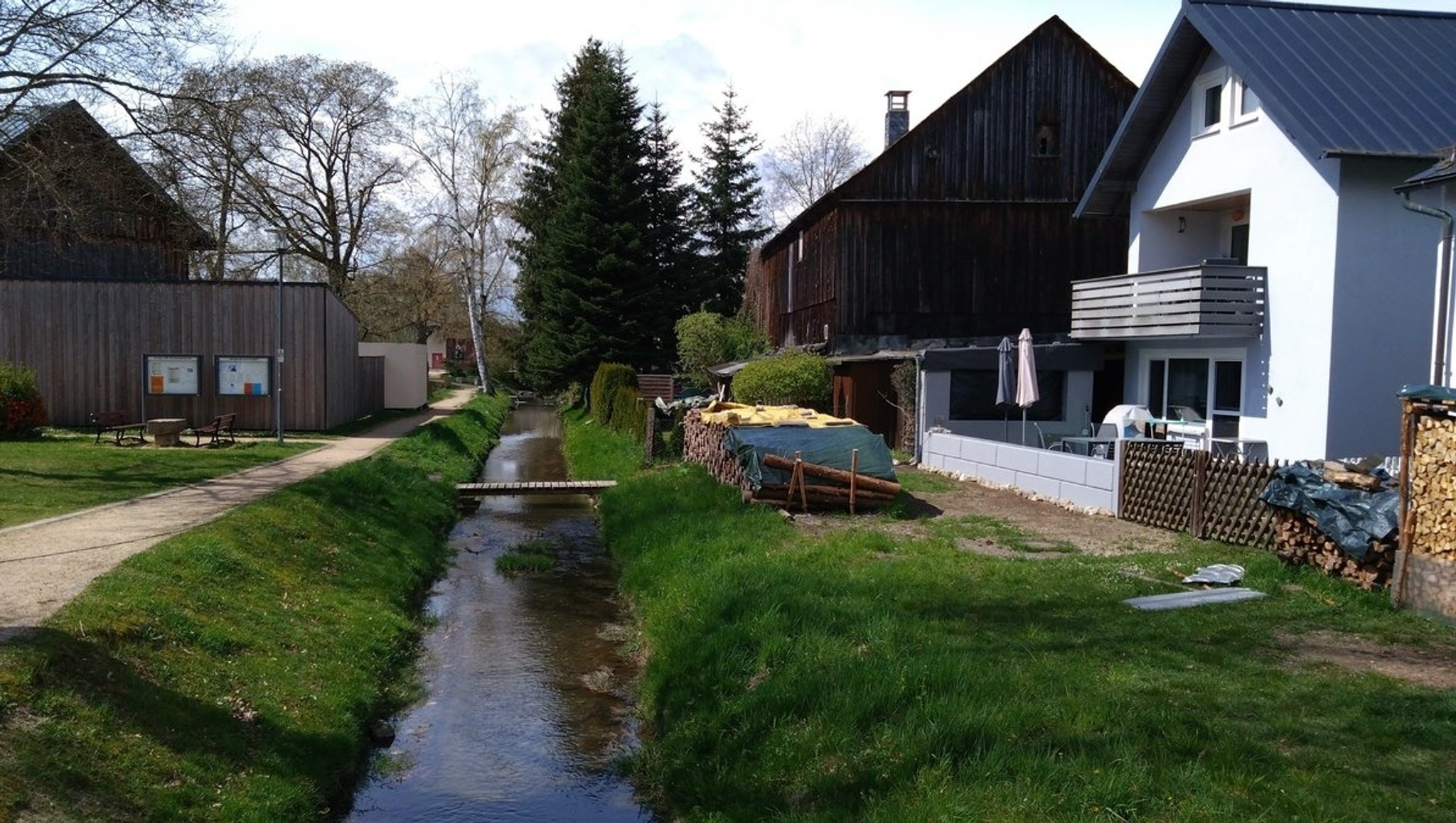 Ein kanalisierter Bachlauf direkt vor einem Haus. 