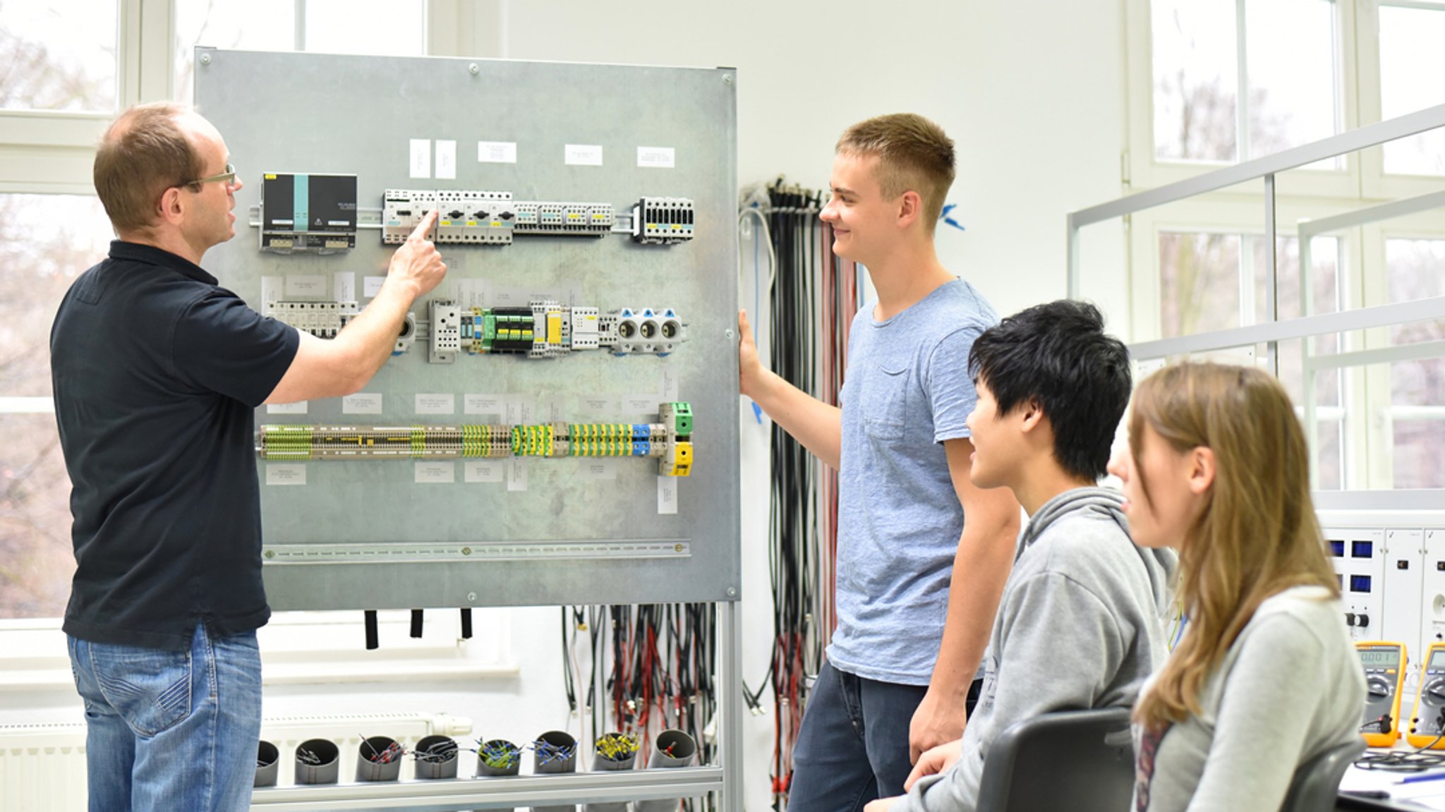 Jugendliche und Lehrer in der Berufsausbildung für Elektrotechnik.
