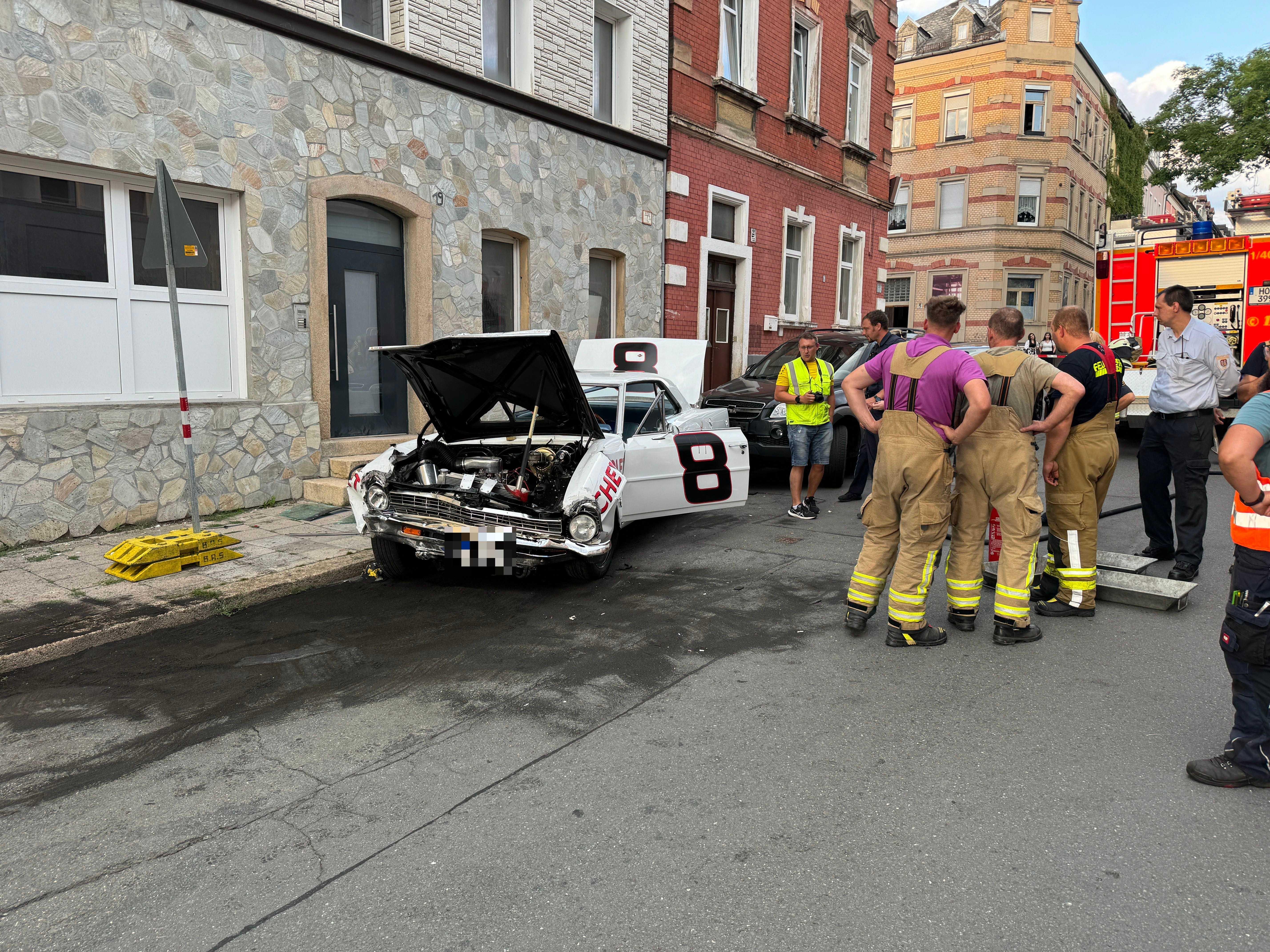 Das Unfallauto steht mit offenen Türen und offener Motorhaube am Straßenrand.